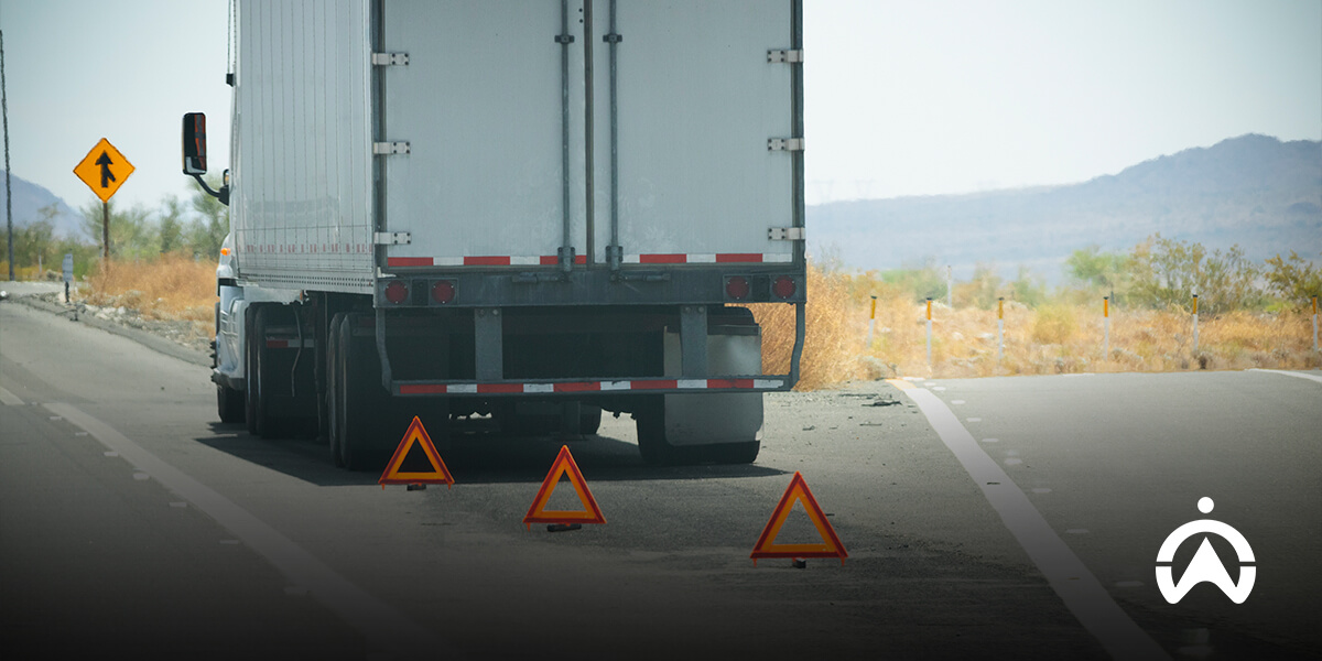 Semi-truck pulled over with hazard triangles on a desolate road.