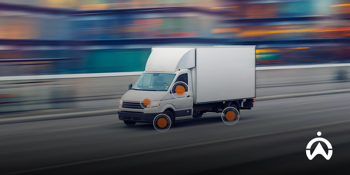 A white delivery truck in motion on a blurred city street.